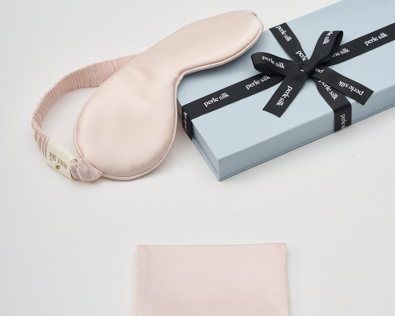 Pink eye mask and pouch with a gift box on a white background