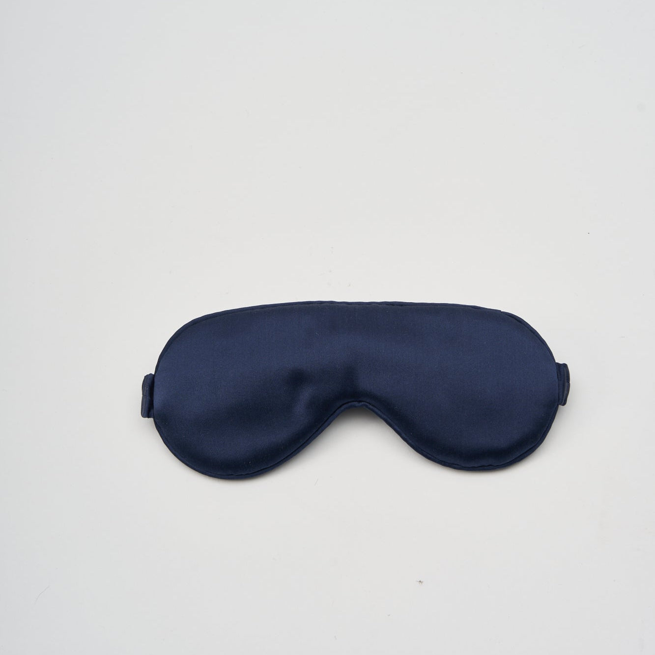 Navy blue silk sleep mask on a light gray background