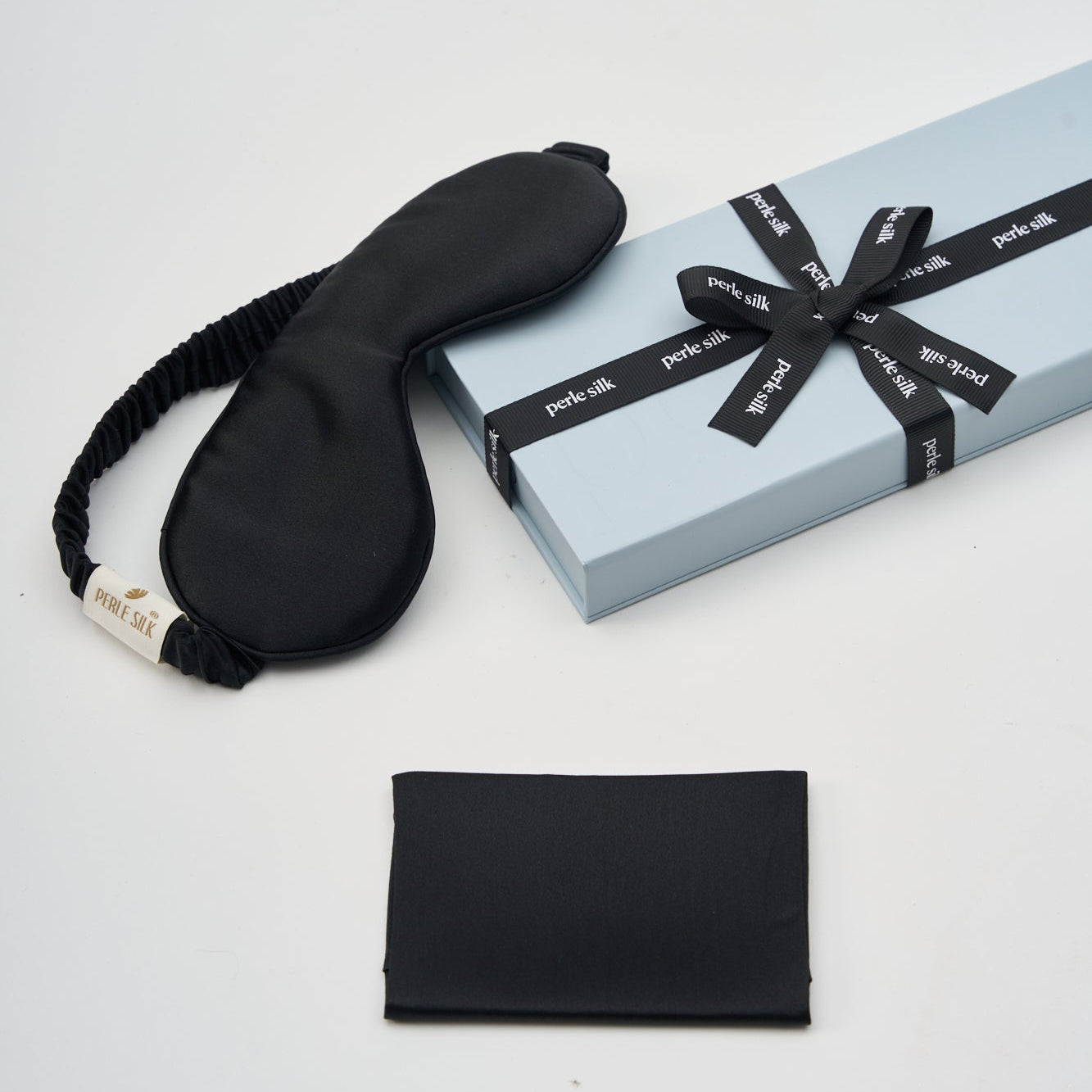 Black silk sleep mask with packaging on a white background